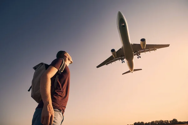 Traveler with backpack watching a plane take off